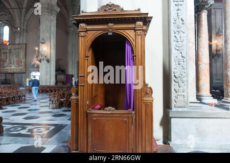 Como Italie - mai 6 2011 ; stand confessionnel en bois ouvert avec rideau violet à l'intérieur de l'église  Banque D'Images