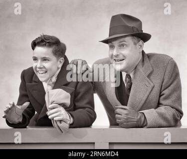 1930s EXCITED CHEERING MAN FATHER AND BOY SON EXCITED SPORTING FANS WEARING WINTER COATS AND GLOVES WATCHING AN ATHLETIC EVENT - s4099 HAR001 HARS OLD FASHION 1 JUVENILE EXCITED STYLE COMPETITION SONS PLEASED FAMILIES JOY LIFESTYLE SATISFACTION CELEBRATION STUDIO SHOT EVENT COPY SPACE FRIENDSHIP HALF-LENGTH FAN PERSONS CARING MALES FATHERS SPECTATORS B&W SPORTING HAPPINESS CHEERFUL ADVENTURE AND DADS EXCITEMENT PRIDE ENTHUSIASTIC SMILES WATCHER CONNECTION JOYFUL SPECTATOR STYLISH SUPPORT THRILLED FATHERS AND SONS MALE BONDING EAGER FANS JUVENILES MID-ADULT MID-ADULT MAN PRE-TEEN PRE-TEEN BOY Stock Photo