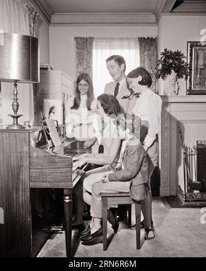 FAMILLE DES ANNÉES 1960 DE 5 CHANTANT AUTOUR DU SALON PIANO MÈRE JOUANT DU PIANO ET 3 ENFANTS ET DAD CHANTANT - M8991 HARS DAD MOM À L'INTÉRIEUR MUSICAL NOSTALGIQUE AUTOUR DE PAIRE SUBURBAINES URBAINES VIEUX TEMPS OCCUPÉ NOSTALGIE FRÈRE VIEILLE MODE SŒUR CHANTEUSE DE COMMUNICATION JUVÉNILE JEUNE ADULTE CHANTEURS DE TRAVAIL D'ÉQUIPE FILS FAMILLES JOIE STYLE DE VIE MUSICIEN SONORE FEMMES MARIÉES 5 FRÈRES ÉPOUX ÉPOUX ÉPOUX ACCUEIL VIE COPIE ESPACE AMITIÉ DEMI-LONGUEUR DAMES FILLES PERSONNES INSPIRATION MÂLES ADOLESCENTE DIVERTISSEMENT FRÈRES SŒURS PÈRES B&W PARTENAIRE ACTIVITÉ BONHEUR BIEN-ÊTRE LOISIRS ET CHANSON D'EXCITATION DADS Banque D'Images