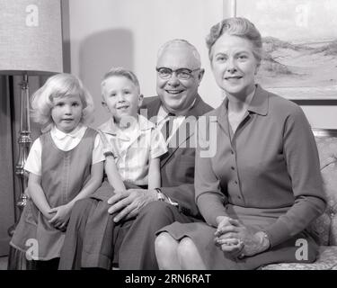 1960s PORTRAIT OF TWO GRANDPARENTS ON COUCH WITH TWO GRAND CHILDREN A BOY AND GIRL ALL LOOKING AT CAMERA - j11044 HAR001 HARS LIFESTYLE FEMALES MARRIED GRANDPARENT SPOUSE HUSBANDS HEALTHINESS HOME LIFE COPY SPACE FRIENDSHIP HALF-LENGTH LADIES PERSONS CARING MALES CONFIDENCE SENIOR MAN SENIOR ADULT B&W PARTNER EYE CONTACT SENIOR WOMAN DREAMS HAPPINESS EXCITEMENT PRIDE YOUNG AND OLD GENERATION GRANDMOTHERS RELATIONSHIPS CONNECTION GRANDDAUGHTER GRANDFATHERS GRANDSON RELATED STYLISH AGE DIFFERENCE GROWTH TOGETHERNESS WIVES BLACK AND WHITE CAUCASIAN ETHNICITY GRANDMA GRANDPA HAR001 OLD FASHIONED Stock Photo