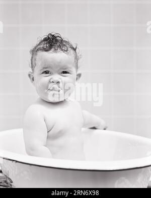 1940S SOURIANT BÉBÉ FILLE ASSISE DANS LA BAIGNOIRE REGARDANT LA LANGUE DE LA CAMÉRA LÉCHER LA LÈVRE SUPÉRIEURE - B8783 HARS BRUNETTE HUMORISTIQUE LÉCHER EXCITATION COMÉDIE COMIQUE SORTIR DE LA LANGUE AGRÉABLE AGRÉABLE CHARMANTE COOPÉRATION CROISSANCE JEUNES LÈVRES ADORABLES AGRÉABLE ADORABLE ATTIRANTE BÉBÉ FILLE NOIR ET BLANC CAUCASIEN ETHNICITÉ HAR001 OLD FASHIONED Banque D'Images