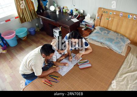 (150812) -- NANNING, 12 août 2015 -- l'enfant de 7 ans Mei Mohan, originaire de la province de Jiangxi de l'est de la Chine, dessine des photos avec ses parents sur un chantier de construction à Nanning, capitale de la région autonome de Guangxi Zhuang du sud de la Chine, 12 août 2015. Près d’un millier de constructeurs de tout le pays travaillent sur le chantier de construction du pont de Lianqing à Nanning City, loin de leurs enfants et de leur domicile. Certains enfants ne peuvent pas attendre jusqu'à la fête du printemps, la seule fois pour leurs parents de rentrer à la maison, mais sont venus à Nanning pour se retrouver pendant leurs vacances d'été.) (MT) CHINA-NANNING-CONSTRUCTION Banque D'Images