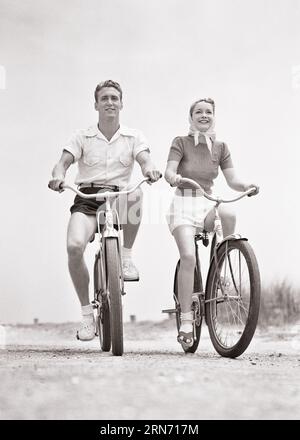 1940S SOURIANT JEUNE COUPLE HOMME ET FEMME PORTANT DES SHORTS CHEVAUCHANT DES VÉLOS DE PLAGE REGARDANT LA CAMÉRA - B17839 HAR001 HARS 1 SHORTS DE FITNESS EN BONNE SANTÉ JEUNE ADULTE ÉQUILIBRE TRAVAIL D'ÉQUIPE VACANCES HEUREUX JOIE STYLE DE VIE FEMMES MARIÉES VÉLO CONJOINT RURAL MARIS SANTÉ ESPACE COPIE AMITIÉ PLEINE LONGUEUR FEMMES FITNESS PERSONNES INSPIRATION HOMMES SÉRÉNITÉ VERS CONFIANCE TRANSPORT VÉLOS PARTENAIRE B&W BIKES CONTACT VISUEL LIBERTÉ OBJECTIFS TEMPS LIBRE ACTIVITÉ BONHEUR BIEN-ÊTRE PHYSIQUE JOYEUSE AVENTURE LOISIR FORCE VOYAGE ET ESCAPADE EXCITATION FAIBLE ANGLE RÉCRÉATION DIRECTION FIERTÉ OPPORTUNITÉ Banque D'Images