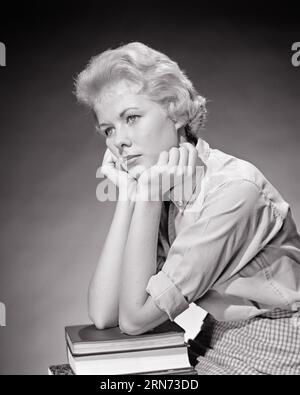 1950s SAD THOUGHTFUL BLONDE TEENAGE GIRL YOUNG WOMAN STUDENT RESTING ELBOWS ON TEXTBOOKS AND HEAD IN HER HANDS - s6230 HAR001 HARS OLD TIME FUTURE NOSTALGIA OLD FASHION 1 JUVENILE FACIAL FEAR BLOND YOUNG ADULT WORRY LIFESTYLE FEMALES MOODY LADIES PENSIVE PERSONS THOUGHTFUL INSPIRATION TEENAGE GIRL EXPRESSIONS TROUBLED B&W CONCERNED RESTING SADNESS GOALS SCHOOLS DREAMS UNIVERSITIES AND CHOICE KNOWLEDGE REFLECTIVE THINK HIGH SCHOOL MOOD REFLECTING ELBOWS HIGH SCHOOLS HIGHER EDUCATION PONDER PONDERING CONSIDER LOST IN THOUGHT TEXTBOOKS GLUM STYLISH TEENAGED COLLEGES CONTEMPLATIVE SINCERE MEDITATE Stock Photo