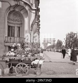 1960s FLOWERS FOR SALE ON SIDEWALK OF THE CHAMPS-ELYSEES WITH THE ARC DE TRIOMPHE IN BACKGROUND PARIS FRANCE - r10804 BAU001 HARS LADIES PERSONS SCENIC AUTOMOBILE MALES BUILDINGS PEDESTRIANS TRANSPORTATION EUROPE B&W ARC PEDESTRIAN STRUCTURE ADVENTURE EUROPEAN PROPERTY CUSTOMER SERVICE AUTOS CHOICE EXTERIOR CAPITAL REAL ESTATE DE STRUCTURES AUTOMOBILES CITIES VEHICLES EDIFICE STREET SCENE ARC DE TRIOMPHE BLACK AND WHITE CAUCASIAN ETHNICITY CHAMPS ELYSEES OLD FASHIONED PARISIAN TRIOMPHE Stock Photo