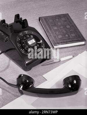 1950s 1960s STILL LIFE OF ROTARY DIAL BLACK PHONE OFF THE HOOK A OEN AND ADDRESS BOOK NOTE PAD - s10390 HAR001 HARS REPRESENTATION Stock Photo