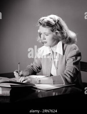 FILLE ADOLESCENTE DES ANNÉES 1950 ASSISE À LA MAISON BUREAU ÉTUDIANT LE LIVRE DE LECTURE ET L'ÉCRITURE DE NOTES PORTANT UN GILET TRICOTÉ AVEC CHEMISIER ET POIGNET MONTRE - S1298 HAR001 HARS VIEILLE MODE 1 JEUNESSE COMMUNICATION POIGNET NOTES JOIE STYLE DE VIE SATISFACTION FEMMES MAISON VIE COPIE ESPACE DEMI-LONGUEUR DAMES PERSONNES RÉFLÉCHIES TEENAGE GIRL CONFIANCE B&W TRICOT ÉCOLES RÊVES STRATÉGIE DE DÉCOUVERTE UNIVERSITÉS ET CONNAISSANCES BLOUSE LYCÉE LYCÉE ÉCOLES ENSEIGNEMENT SUPÉRIEUR CONCEPTUEL ÉLÉGANT COLLÈGES ADOLESCENTS SINCÈRE SOLENNEL CARDIGAN FOCALISÉ CROISSANCE INTENSE JUVÉNILES RELAXATION NOIR ET BLANC PRUDENT CAUCASIEN ETHNICITÉ EARNEST HAR001 Banque D'Images