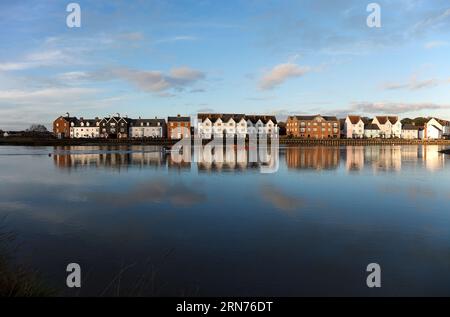 Tard dans l'après-midi de décembre, un lotissement riverain de propriété nouvelle, ancienne et rénovée brille presque en couchant la lumière du soleil sous un ciel bleu. Banque D'Images