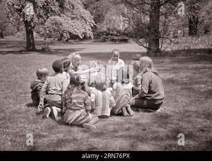 ENSEIGNANTE ADULTE DES ANNÉES 1960 DONNANT UNE BALLE À UN GROUPE ETHNIQUEMENT MIXTE D'ENFANTS DE DIFFÉRENTS ÂGES ASSIS EN CERCLE SUR LE GAZON DE PARC - J12340 HAR001 HARS HEALTHY INNESS COPIE ESPACE AMITIÉ DEMI-LONGUEUR DAMES PERSONNES INSPIRATION DONNER AUX HOMMES B&W ÂGES MÉLANGÉS BONHEUR GRAND ANGLE AVENTURE DÉCOUVERTE LOISIRS AFRO-AMÉRICAINS AFRICAN-AMERICAN EXCITATION INSTRUCTEUR ETHNICITÉ NOIRE OCCUPATIONS ÉDUCATEUR CONCEPTUEL DIVERS APRÈS L'ÉCOLE COOPÉRATION ÉDUQUANT LES ÉDUCATEURS ETHNIQUEMENT LA CROISSANCE INSTRUCTEURS JUVÉNILES ÉCOLE ENSEIGNE ENSEMBLE JEUNE FEMME ADULTE NOIR ET BLANC ETHNICITÉ CAUCASIENNE HAR001 OLD FASHIONED Banque D'Images