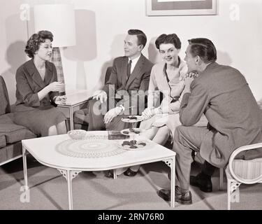 1950s 1960s TWO COUPLES SITTING AROUND COFFEE TABLE ENGAGED IN CONVERSATION MEN WEARING SUITS AND TIES WOMEN IN DRESSES - s10495 HAR001 HARS SPOUSE HUSBANDS HOME LIFE COPY SPACE FRIENDSHIP HALF-LENGTH LADIES PERSONS MALES B&W PARTNER DRESSES SUIT AND TIE HAPPINESS HIGH ANGLE DISCOVERY AND NETWORKING ENGAGED CONNECTION FRIENDLY STYLISH TIES VISIT VISITING SOCIALIZE COOPERATION MID-ADULT MID-ADULT MAN MID-ADULT WOMAN TOGETHERNESS WIVES YOUNG ADULT MAN YOUNG ADULT WOMAN BLACK AND WHITE CAUCASIAN ETHNICITY HAR001 OLD FASHIONED Stock Photo