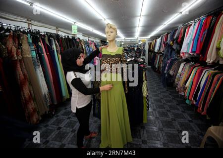 (150912) -- NAPLOUSE, 12 septembre 2015 -- Une vendeuse palestinienne expose des vêtements chinois dans son magasin, dans la ville de Naplouse en Cisjordanie, le 12 septembre 2015. Pour de nombreux hommes d'affaires palestiniens, les produits chinois sont de bons choix en raison du prix bon marché. À Naplouse, la Chine est un mot commun à tout le monde, et les produits fabriqués en Chine sont partout sur les marchés et vendus à des prix raisonnables.) MIDEAST-NAPLOUSE-PRODUIT CHINOIS NidalxEshtayeh PUBLICATIONxNOTxINxCHN Naplouse sept 12 2015 une vendeuse PALESTINIENNE expose une robe chinoise À son magasin dans la ville de Naplouse en CISJORDANIE LE 12 2015 septembre pour DE NOMBREUX hommes d'affaires PALESTINIENS Banque D'Images