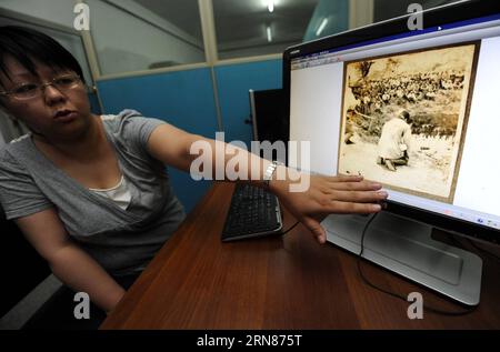 La photo prise le 12 juin 2014 montre un membre du personnel présentant des photos prises par les envahisseurs japonais au sujet du massacre de Nanjing aux deuxièmes Archives historiques de Chine à Nanjing, capitale de la province de Jiangsu de l'est de la Chine. Au total, 47 nouvelles candidatures, y compris les documents du massacre de Nankin en provenance de Chine, sont inscrites au Registre mémoire du monde par le Comité consultatif international du Programme mémoire du monde de l UNESCO, a annoncé l UNESCO dans un communiqué de presse du 9 octobre 2015. FRANCE-PARIS-DOCUMENTS-NANJING MASSACRE-MÉMOIRE DU REGISTRE MONDIAL HANXYUQING PUBLICATIONXNOTXINXCH Banque D'Images