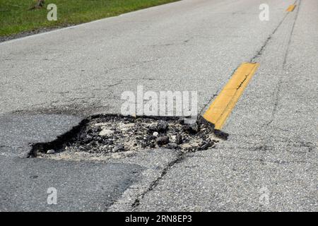 Un dangereux nid d'poule sur la surface de la route américaine. Allée détruite, nécessitant une réparation urgente Banque D'Images