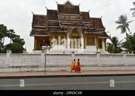 Deux moines bouddhistes marchant dans la rue devant un temple à Luang Prabang, Laos Banque D'Images