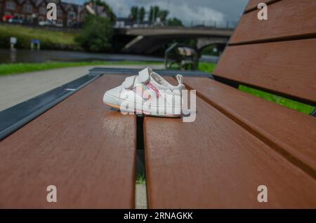 Chaussure perdue d'enfant assis sur un banc de parc sur les rives du Lough Erne Banque D'Images