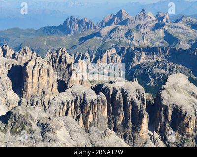 VUE AÉRIENNE. Le paysage incroyablement déchiqueté du massif de la Sella avec le parc naturel de Puez-Geisler au loin. Dolomites, Italie. Banque D'Images