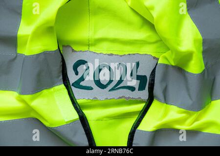 2024 written in green paint lies on a reflective vest, Happy New Year 2024, banner and background, special clothing and work Stock Photo