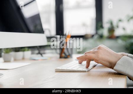 vue recadrée de femme d'affaires mature tapant sur le clavier près de l'écran d'ordinateur dans le bureau Banque D'Images