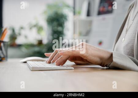 vue recadrée de femme d'âge moyen tapant sur le clavier tout en travaillant dans le bureau Banque D'Images