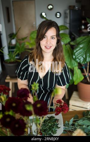 Woman looking at camera while assembling flower bouquet Stock Photo