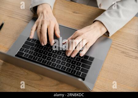 cropped view of middle aged businesswoman typing on laptop in modern office, top view Stock Photo