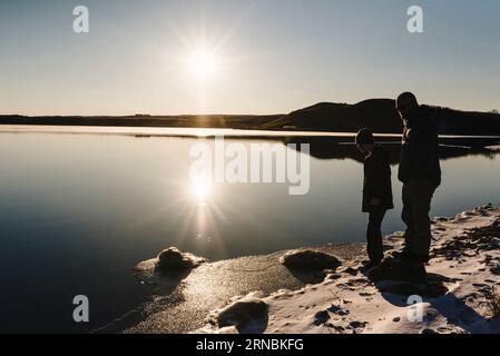 Père et fils se tiennent sur le bord du lac gelé pendant l'hiver Banque D'Images