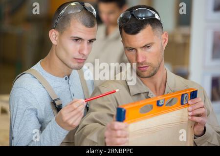 Deux homme mur holding spirit level Banque D'Images