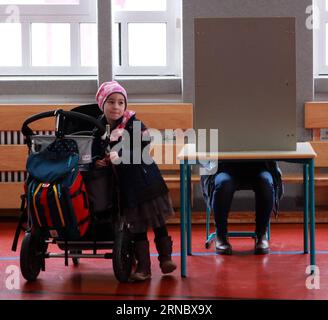 (160313) -- MAYENCE, 13 mars 2016 -- Daniela Moerscher remplit le bulletin de vote pendant que sa fille attend à ses côtés dans un bureau de vote à Mayence, Allemagne, le 13 mars 2016. Les élections nationales dans trois États allemands : Rhénanie-Palatinat, Saxe-Anhalt et Bade-Wuerttemberg, ont lieu dimanche, ce qui est un test crucial pour la chancelière allemande et présidente des démocrates chrétiens allemands (CDU) Angela Merkel, qui est soumise à une pression croissante sur sa politique d'immigration envers les migrants et les réfugiés. Le parti anti-migration allemand, l'alternative pour l'Allemagne a un nombre de sondages solides et la volonté Banque D'Images