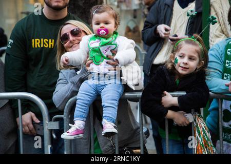 (160317) -- NEW YORK, le 17 mars 2016 -- Une femme tient son bébé pendant la Saint Patrick s Day Parade à New York, aux États-Unis, le 17 mars 2016. Des centaines de milliers de personnes se sont rassemblées le long de la Cinquième Avenue de New York pour observer la rue Patrick s Day Parade ici jeudi. ) ÉTATS-UNIS-NEW YORK-ST. PATRICK S DAY-PARADE LixChangxiang PUBLICATIONxNOTxINxCHN New York Mars 17 2016 une femme tient son bébé pendant la St Patrick S Day Parade à New York les Etats-Unis Mars 17 2016 des centaines de milliers de célébrités se sont rassemblées aux côtés de New York S Fifth Avenue pour regarder la St Patrick S Banque D'Images