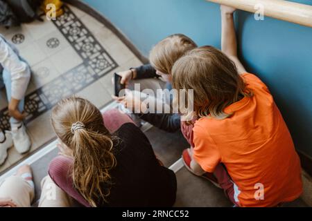 Vue à angle élevé des amis masculins et féminins assis sur l'escalier du bâtiment de l'école Banque D'Images