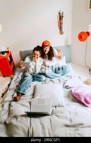 Heureux amis féminins appel vidéo via téléphone intelligent à la maison Banque D'Images