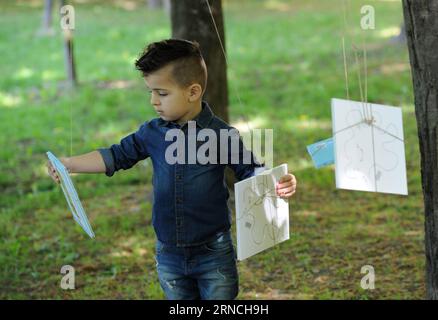 (160412) -- ZAGREB, 12 avril 2016 -- Un garçon choisit un livre accroché dans les arbres lors de la cérémonie d'ouverture du 9e Festival du livre pour enfants au parc Tresnjevka à Zagreb, capitale de la Croatie, le 12 avril 2016. L'événement choisir une histoire est organisé pour promouvoir l'habitude de lecture chez les enfants d'âge préscolaire. ) CROATIE-ZAGREB-CHILDREN S BOOK FESTIVAL MisoxLisanin PUBLICATIONxNOTxINxCHN 160412 Zagreb avril 12 2016 un garçon choisit un livre accroché dans les arbres lors de la cérémonie d'ouverture du 9e Festival du livre pour enfants S AU Parc Tresnjevka à Zagreb capitale de la Croatie avril 12 2016 Pick a Story Event EST organisé pour pro Banque D'Images
