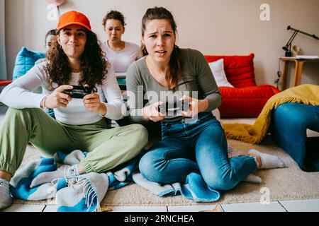 Jeunes amies jouant au jeu vidéo à la maison Banque D'Images