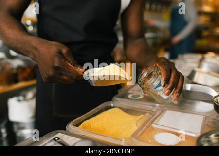 Section médiane du propriétaire du magasin remplissant la nourriture dans le pot Banque D'Images