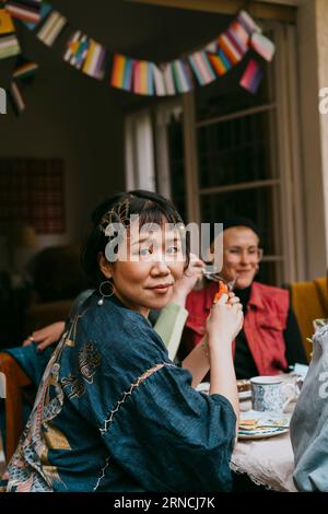 Portrait de vue latérale de transwoman assis avec des amis pendant la fête dans la cour arrière Banque D'Images