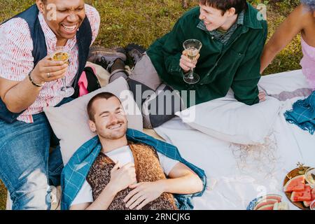 Vue à grand angle des amis de la communauté LGBTQ s'amusant pendant le dîner dans la cour arrière Banque D'Images