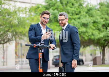 Hommes d'affaires utilisant le téléphone portable en plein air. Homme d'affaires mature confiant parlant sur le téléphone portable tout en marchant à l'extérieur. Hommes d'affaires regardant les messages Banque D'Images