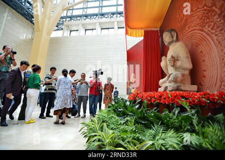 (160430) -- SHIJIAZHUANG, April 30, 2016 -- Visitors view the complete Buddha statue at Hebei Museum in Shijiazhuang, capital of north China s Hebei Province, April 30, 2016. The white marble Buddha statue, which was made around 556 by North Qi dynasty, was originally worshipped at Youju Temple in Hebei Province, where the Buddha s head was stolen in 1996. Master Hsing Yun, founder of Fo Guang Shan Monastery in southeast China s Taiwan, decided to return the 80 kg statue head to the mainland after it was presented to him by a follower in 2014. The complete statue is now housed at Hebei Museum. Stock Photo