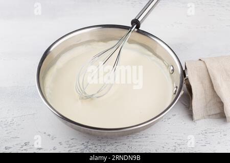 Préparation de sauce au fromage pour pâtes. Ajouter le lait et mélanger jusqu'à obtention d'une crème. DIY étape par étape 6 Banque D'Images