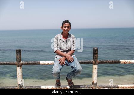 (160527) -- GAZA, le 27 mai 2016 -- Ibrahim al-Nemnem, un enfant palestinien de 13 ans, est vu assis dans le camp de réfugiés de Shati dans la ville de Gaza, le 22 mai 2016. Al-Nemnem qui a grandi entre les ruelles étroites du camp de réfugiés de Shati, rêve d’être ingénieur pour contribuer au développement du camp et améliorer la vie de ses habitants. Alors que le monde célèbre la Journée internationale pour la protection des enfants le 1 juin, al-Nemnem et ses pairs occupent leurs jeunes esprits avec de grands rêves d'une vie meilleure, plus sûre et plus stable dans l'une des régions les plus durement touchées et les plus dangereuses du monde. Banque D'Images