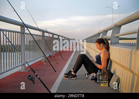 (160531) -- BELGRADE, May 31, 2016 -- A girl fishes and meanwhile enjoys sunset at Pupin Bridge in Belgrade, Serbia, on May 23. 2016. The Bridge, named after Serbian scientist and inventor Mihajlo Pupin, was opened by Premier of the People s Republic of China Li Keqiang and his Serbian counterpart Aleksandar Vucic on December 18, 2014. As the second bridge over the Danube river in Belgrade, it has ended the history that for 70 years there was only one bridge in Belgrade over Danube. Connecting Zemun on the south of Danube and Borca on the north, the bridge has shortened the travel time from mo Stock Photo