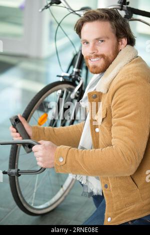 l'homme verrouille la serrure de vélo sur le parking de vélo Banque D'Images