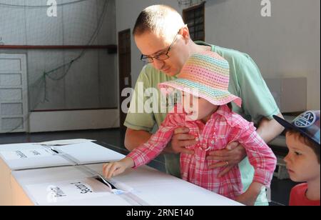 Kommunalwahlen in Rumänien (160605) -- BUCAREST, le 5 juin 2016 -- Un homme laisse sa fille voter dans l'un des bureaux de vote de Bucarest, capitale de la Roumanie, le 5 juin 2016. Les élections locales sont en cours en Roumanie le 5 juin 2016, avec plus de 18 millions d'électeurs pour élire les autorités de l'administration locale. Selon les statistiques publiées par le Bureau électoral central, un certain nombre de 18 616 bureaux de vote ont été ouverts dans tout le pays, et pas moins de 267 242 sont candidats à la mairie, au conseil local ou au conseil de comté. Douze candidats sont en lice pour le bureau du maire général de la capitale. Banque D'Images