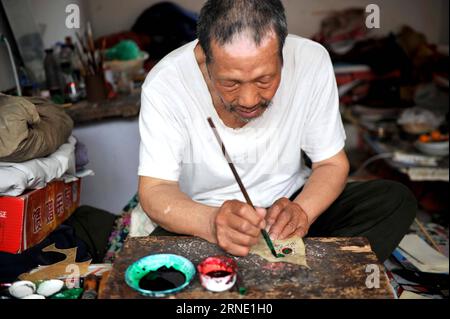 (160606) -- TIANJIN, 5 juin 2016 -- l'artiste de marionnettes d'ombre Zhang Kui colore les marionnettes d'ombre à la maison à Tianjin, dans le nord de la Chine, le 5 juin 2016. Zhang Kui, né en 1937, est aujourd'hui héritier de marionnettes d'ombre. Il a dépendu des marionnettes de l'ombre pour vivre pendant 68 ans depuis son enfance. Mon père avait 38 boîtes d'ombre, mon frère a joué et j'ai sculpté les marionnettes d'ombre, a déclaré l'héritier quand il s'est souvenu de son enfance. De nos jours, moins de gens aiment la performance de marionnette d'ombre. Zhang Kui avait une fois deux apprentis, mais les deux ont finalement abandonné et ont réalisé d'autres busi rentables Banque D'Images