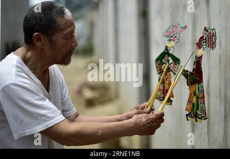 (160606) -- TIANJIN, le 5 juin 2016 -- l'artiste de marionnettes de l'ombre Zhang Kui interprète une pièce de marionnettes de l'ombre à la maison à Tianjin, dans le nord de la Chine, le 5 juin 2016. Zhang Kui, né en 1937, est aujourd'hui héritier de marionnettes d'ombre. Il a dépendu des marionnettes de l'ombre pour vivre pendant 68 ans depuis son enfance. Mon père avait 38 boîtes d'ombre, mon frère a joué et j'ai sculpté les marionnettes d'ombre, a déclaré l'héritier quand il s'est souvenu de son enfance. De nos jours, moins de gens aiment la performance de marionnette d'ombre. Zhang Kui avait une fois deux apprentis, mais les deux ont finalement abandonné et ont mené d'autres profita Banque D'Images