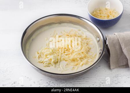 Préparation de sauce au fromage pour pâtes. Ajouter le fromage râpé et remuer. DIY étape par étape 8 Banque D'Images