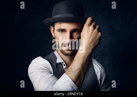 vieux portrait vintage de style anglais sérieux avec la main au chapeau look neutre à la caméra avec les yeux insensibles froids pourrait être un criminel élégant et mod Banque D'Images