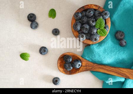 Bleuets dans un bol vintage en bois et une cuillère avec des feuilles de menthe fraîches et saines fruits antioxydants d'été vue de dessus vue aérienne. Banque D'Images