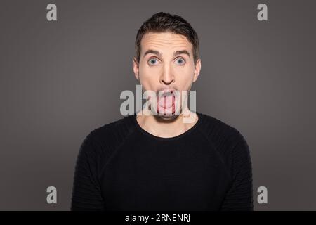 visage grotesque à bouche ouverte d'un homme adulte isolé sur fond gris Banque D'Images