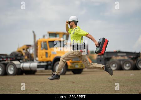 Construction rapide. Drôle de travailleur de la construction sauter. Saut enthousiaste des constructeurs dans le casque. Travailleur dans un casque de sécurité. Ingénieur de construction en saut uniforme de constructeur Banque D'Images